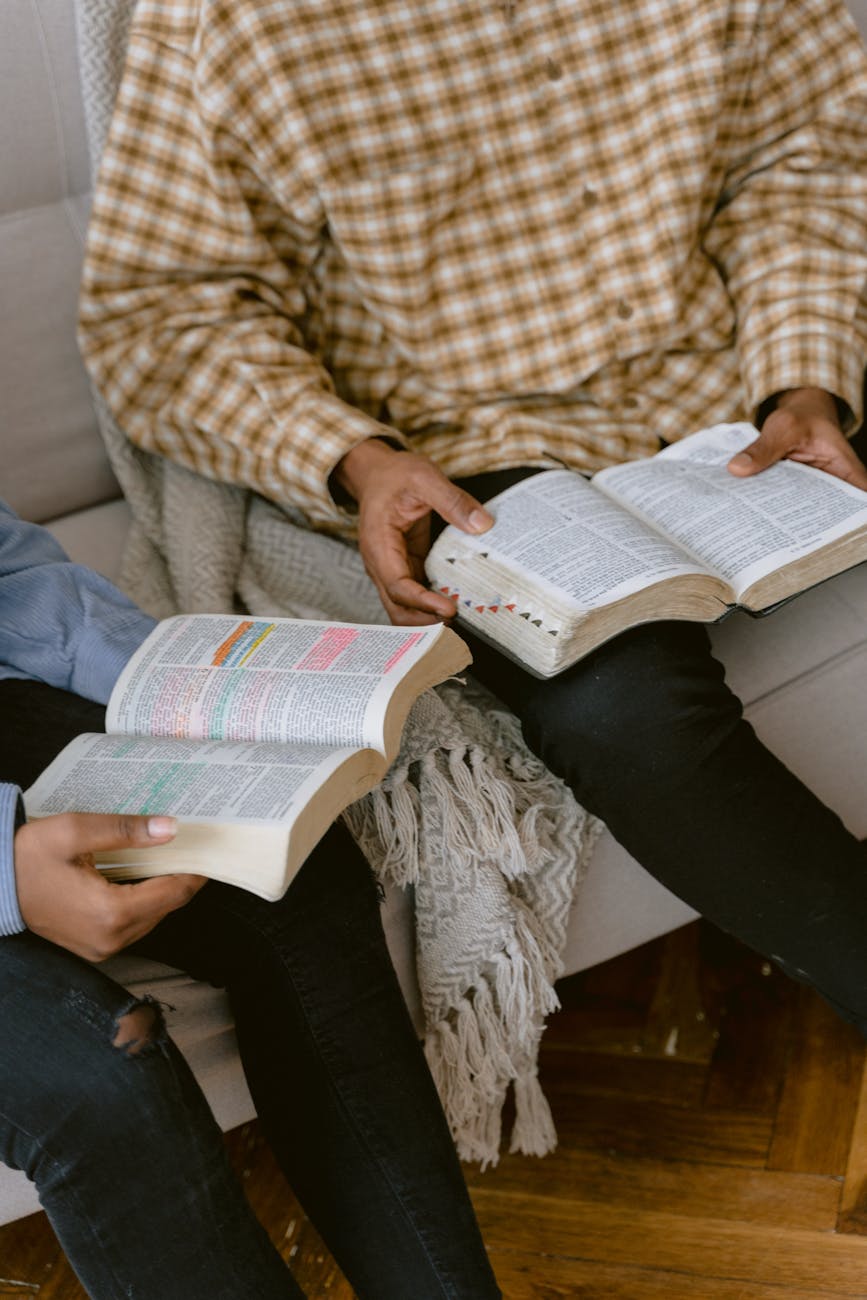 two people reading bible while sitting on a sofa